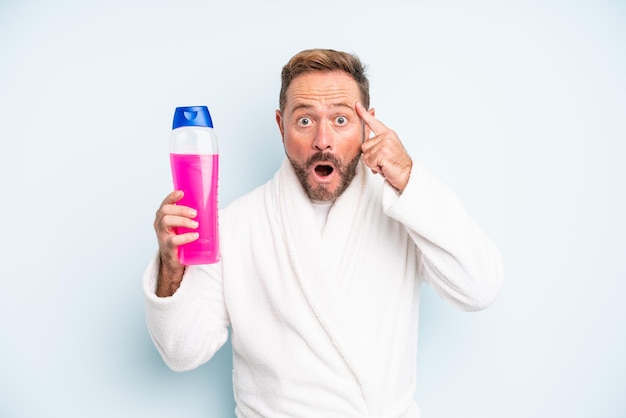 Middle age man looking surprised, realizing a new thought, idea or concept. shampoo bottle