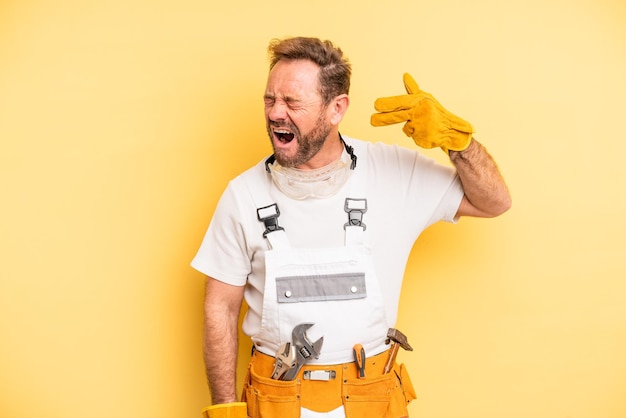 Photo middle age man looking unhappy and stressed suicide gesture making gun sign handyman and repair concept