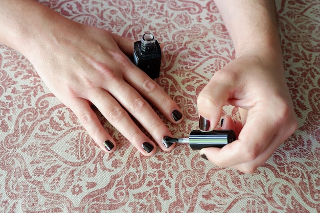 Middle age man painting nails in black colour at home in Madrid Spain Concepts of male makeup