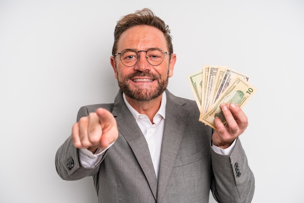 Middle age man pointing at camera choosing you dollar banknotes concept