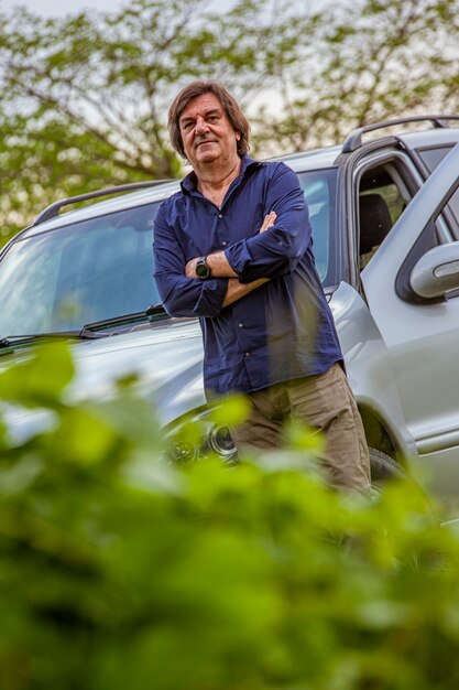 Middle age man portrait in countryside with his car