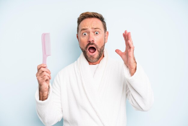 Middle age man screaming with hands up in the air. hair comb concept