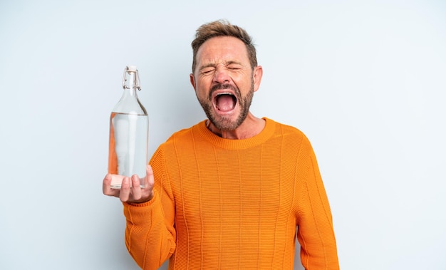Мужчина средних лет агрессивно кричит, выглядя очень злой концепцией бутылки с водой