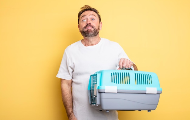 Middle age man shrugging feeling confused and uncertain pet carrier concept