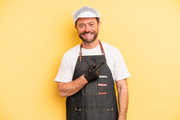 Middle age man smiling cheerfully feeling happy and pointing to the side fishmonger concept