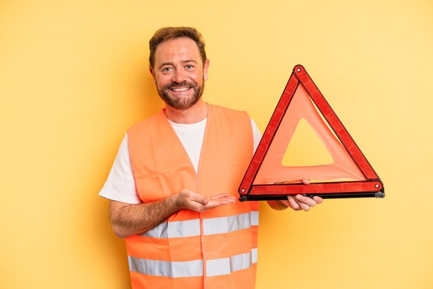 Uomo di mezza età che sorride allegramente, si sente felice e mostra un concetto.. concetto di automobile di ripartizione del triangolo