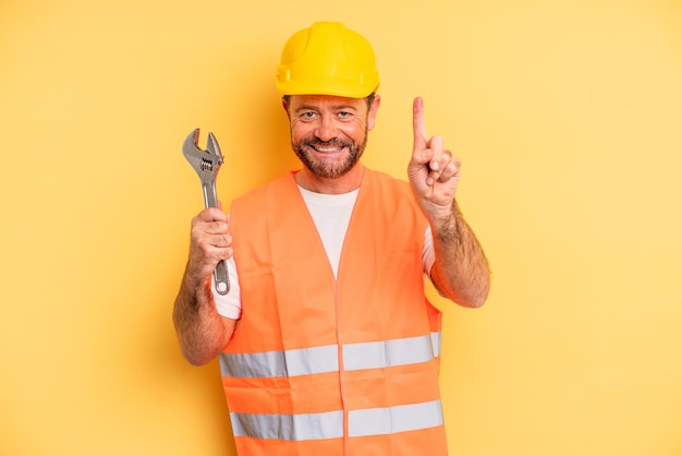 middle age man smiling and looking friendly, showing number one.  breakdown car repair wrench concept