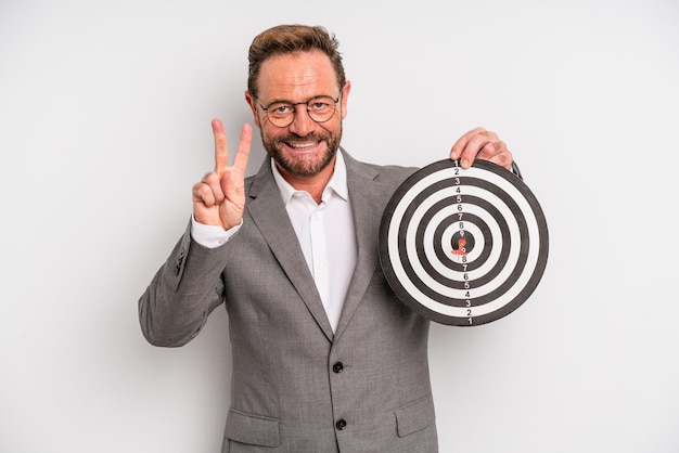 Middle age man smiling and looking friendly, showing number two. target darts concept