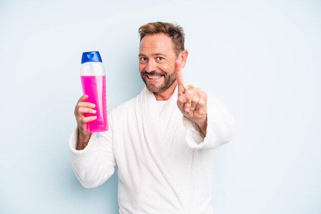 Middle age man smiling proudly and confidently making number one. shampoo bottle