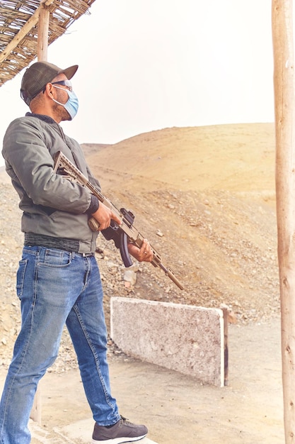 Middle age Man wear Ear plug standing and aiming shotgun at Target in Shooting Range