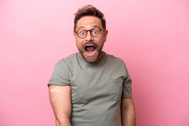 Middle age man wearing a band aids isolated on pink background