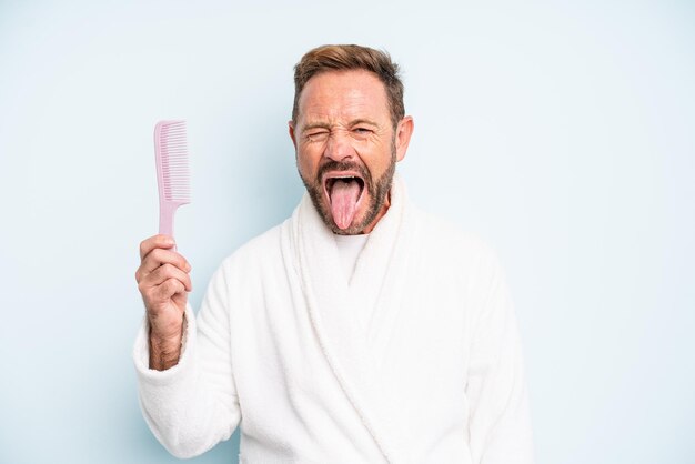 Middle age man with cheerful and rebellious attitude, joking and sticking tongue out. hair comb concept