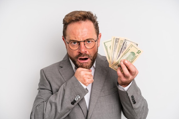 Middle age man with mouth and eyes wide open and hand on chin. dollar banknotes concept