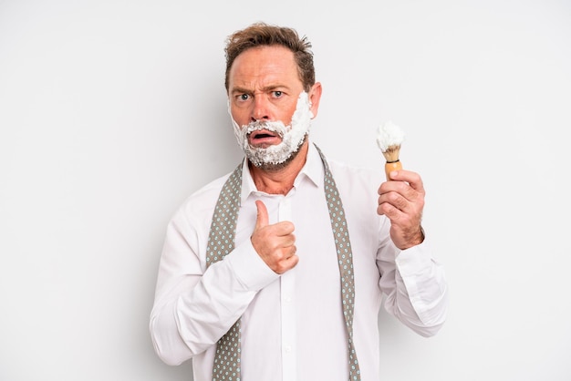 Middle age man with mouth and eyes wide open and hand on chin. shaving brush and foam concept