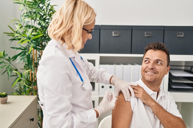 Middle age man and woman doctor and patient vaccinating at clinic