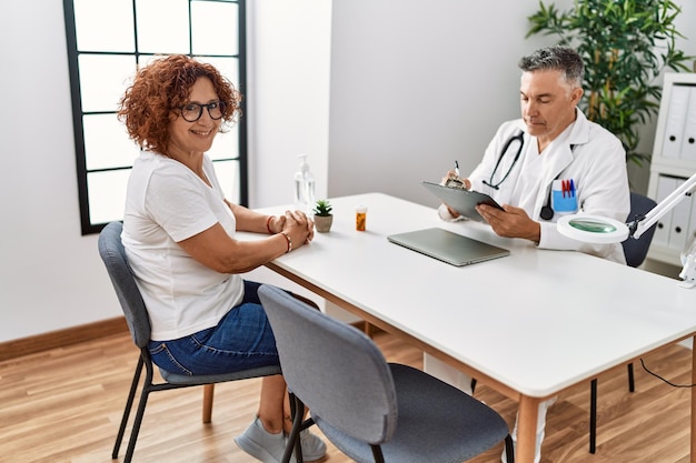 Middle age man and woman wearing doctor uniform having medical consultation at clinic