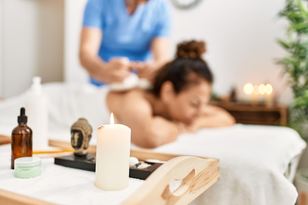 Middle age man and woman wearing therapist uniform having back massage session using thai bags at beauty center