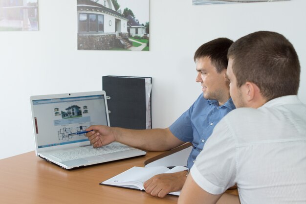 Middle Age Managers Discussing Business While Looking at their Website using Laptop Computer on the Desk.