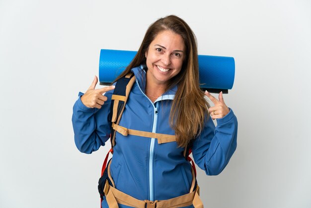 Middle age mountaineer woman with a big backpack giving a thumbs up gesture