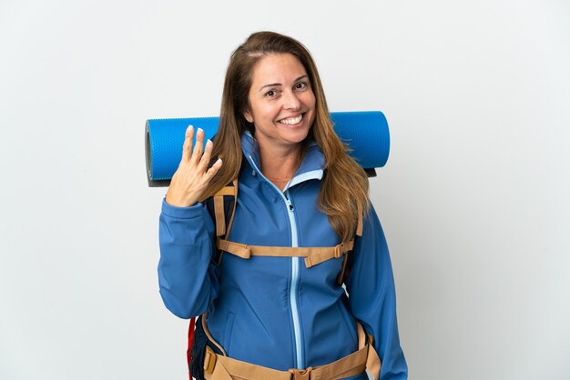 Middle age mountaineer woman with a big backpack happy and counting four with fingers