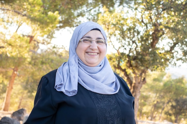 Middle age muslim female wearing hijab looking at camera and smiling as a portrait for female