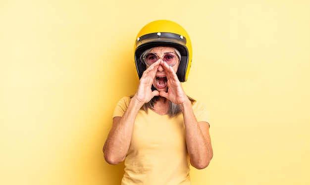 Bella donna di mezza età che si sente felice, dando un grande grido con le mani vicino alla bocca. concetto di casco da moto