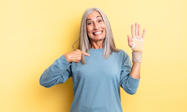 Middle age pretty woman feeling happy and pointing to self with an excited. hand bandage concept