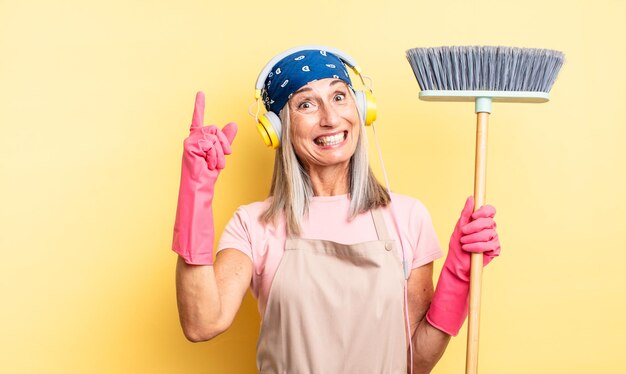 Middle age pretty woman feeling like a happy and excited genius after realizing an idea. household and broom concept