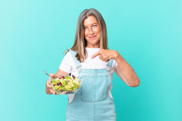 Симпатичная женщина средних лет ест салат.