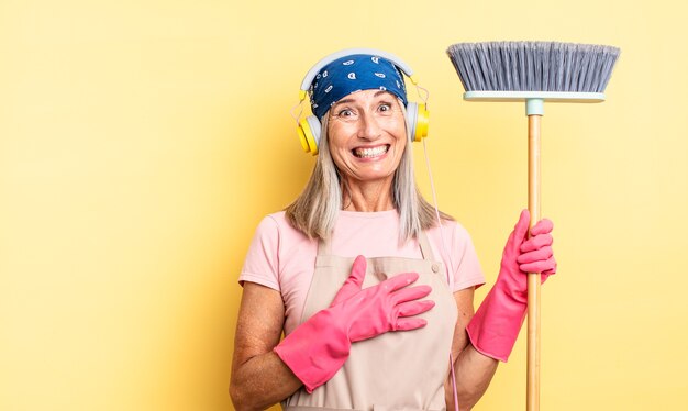 Middle age pretty woman laughing out loud at some hilarious joke. household and broom concept