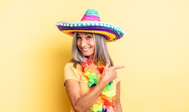 Middle age pretty woman looking excited and surprised pointing\
to the side. mexican party concept