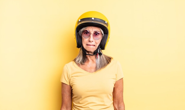 Middle age pretty woman looking puzzled and confused. motorbike helmet concept