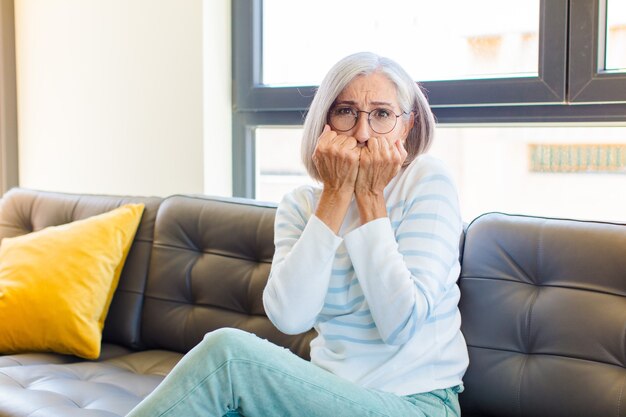 Middle age pretty woman looking worried, anxious, stressed and afraid, biting fingernails and looking to lateral copy space