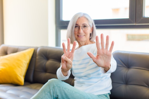 Donna graziosa di mezza età che sorride e sembra amichevole, mostrando il numero otto o ottavo con la mano in avanti, contando alla rovescia