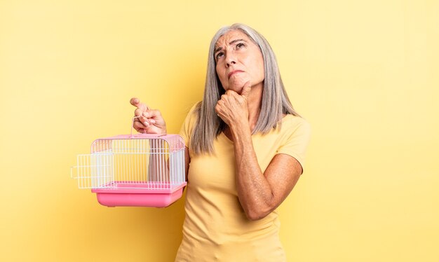 Middle age pretty woman thinking, feeling doubtful and confused. pet cage or jail concept