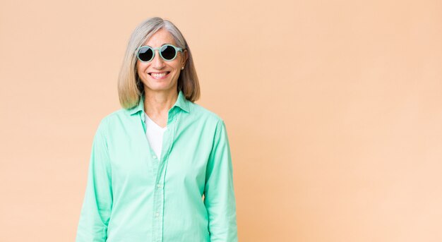 Middle age pretty woman  wearing sunglasses against copy space wall