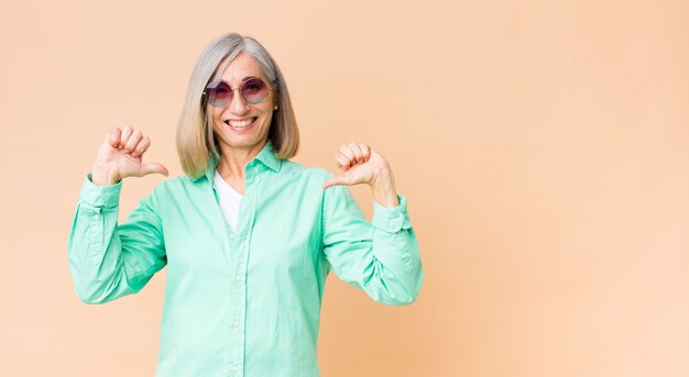 Occhiali da sole d'uso della donna graziosa di medio evo contro la parete dello spazio della copia