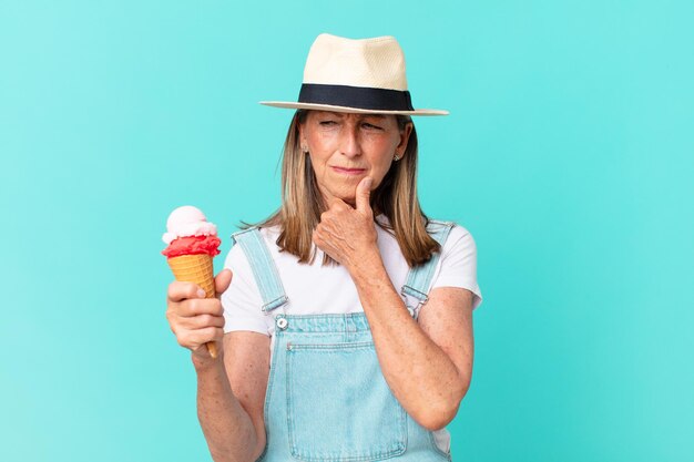 帽子とアイスクリームを保持している中年のきれいな女性。夏のコンセプト