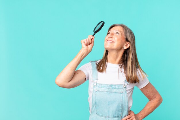 Donna graziosa di mezza età con una lente d'ingrandimento. concetto di ricerca