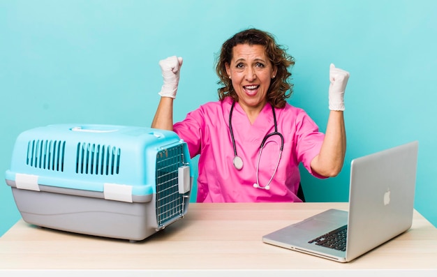 Middle age pretty woman with a pet cage and a laptop veterinarian concept