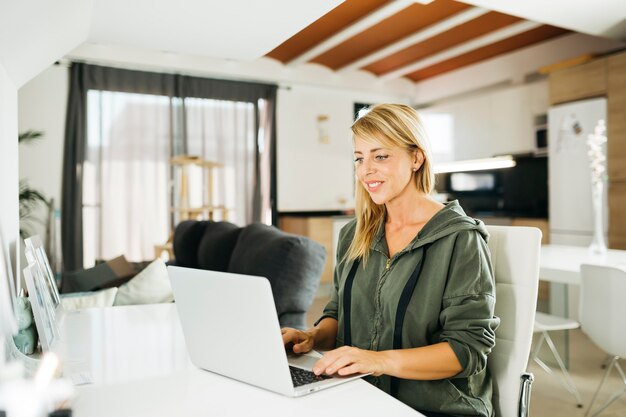 Photo middle age smiling blonde woman using a laptop in a livingroom