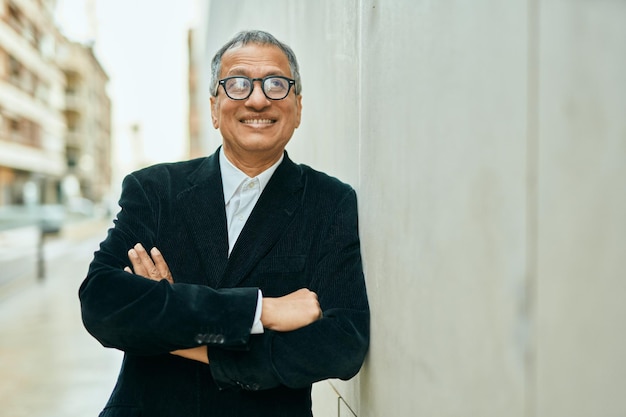 Middle age southeast asian man smiling confident with crossed arms leaning on the wall