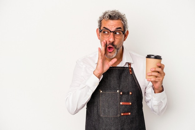 Middle age store clerk holding a take away coffee isolated on\
white background is saying a secret hot braking news and looking\
aside