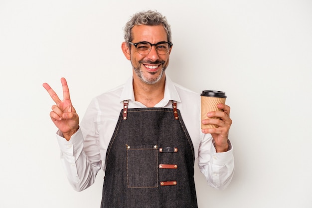 Middle age store clerk holding a take away coffee isolated on white background  joyful and carefree showing a peace symbol with fingers.