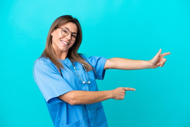 Middle age surgeon woman isolated on blue background pointing finger to the side and presenting a product