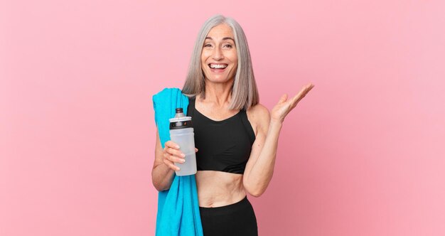 Middle age white hair woman feeling happy, surprised realizing a solution or idea with a towel and water bottle. fitness concept