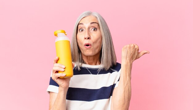 Middle age white hair woman holding a coffee thermos