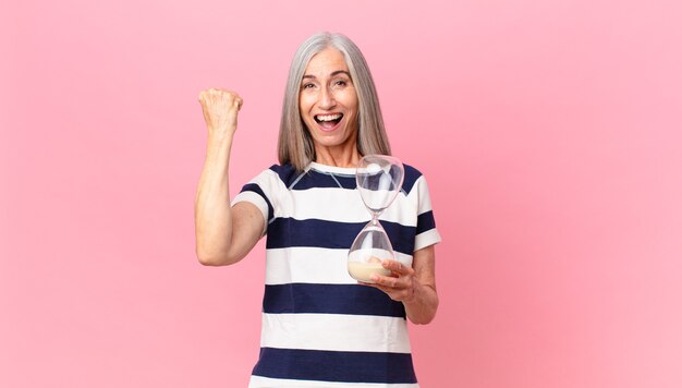 Middle age white hair woman holding a sandglass timer