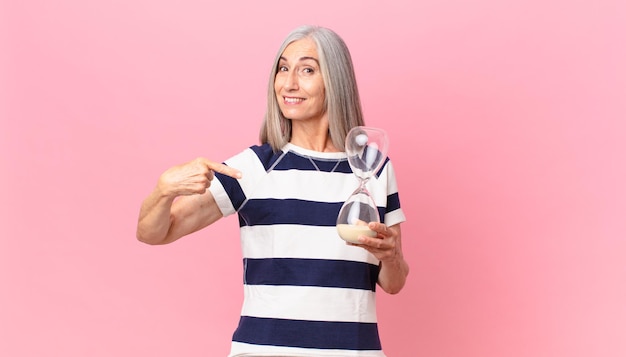 Middle age white hair woman holding a sandglass timer