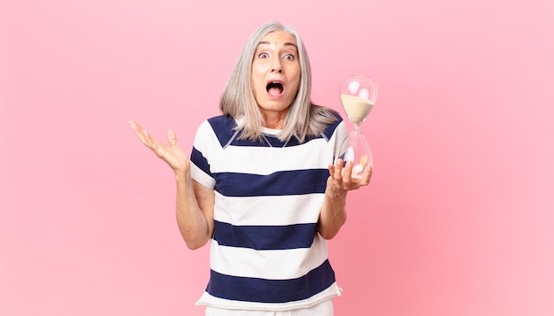 Middle age white hair woman holding a sandglass timer